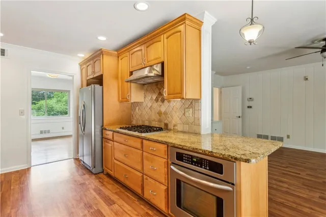 a kitchen with stainless steel appliances granite countertop a stove a sink and a refrigerator