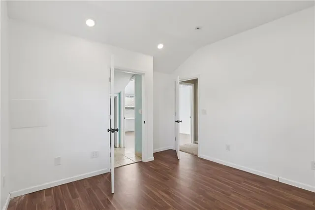 a view of an empty room with wooden floor and closet