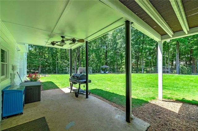 a view of a patio with table and chairs potted plants and floor to ceiling window