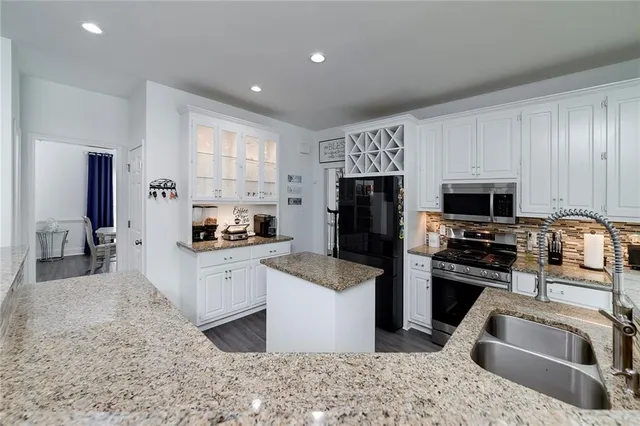 a kitchen with stainless steel appliances a microwave a stove a sink a dining table and chairs