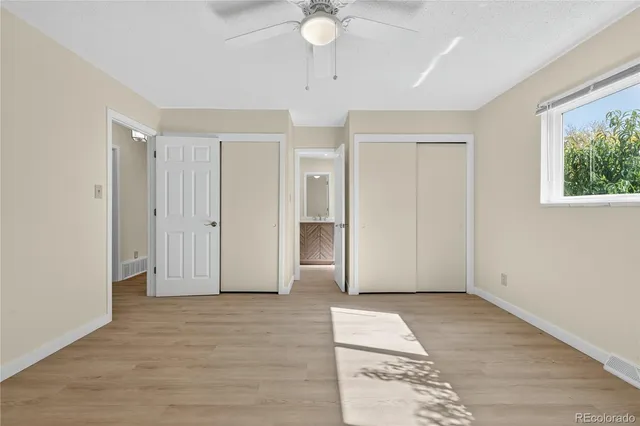 a view of an empty room with window and wooden floor