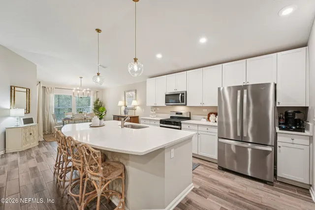 a kitchen with stainless steel appliances a refrigerator a stove a sink dishwasher a oven with a dining table and chairs with wooden floor