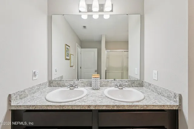 a bathroom with double vanity sinks a vanity and a mirror