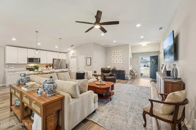 a living room with furniture kitchen view and a chandelier