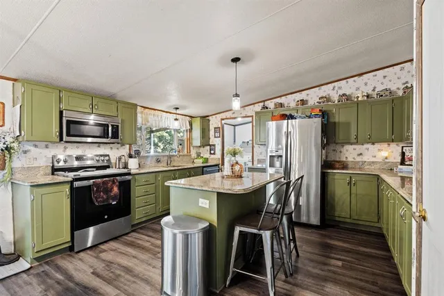 a kitchen with stainless steel appliances kitchen island granite countertop a sink stove and refrigerator