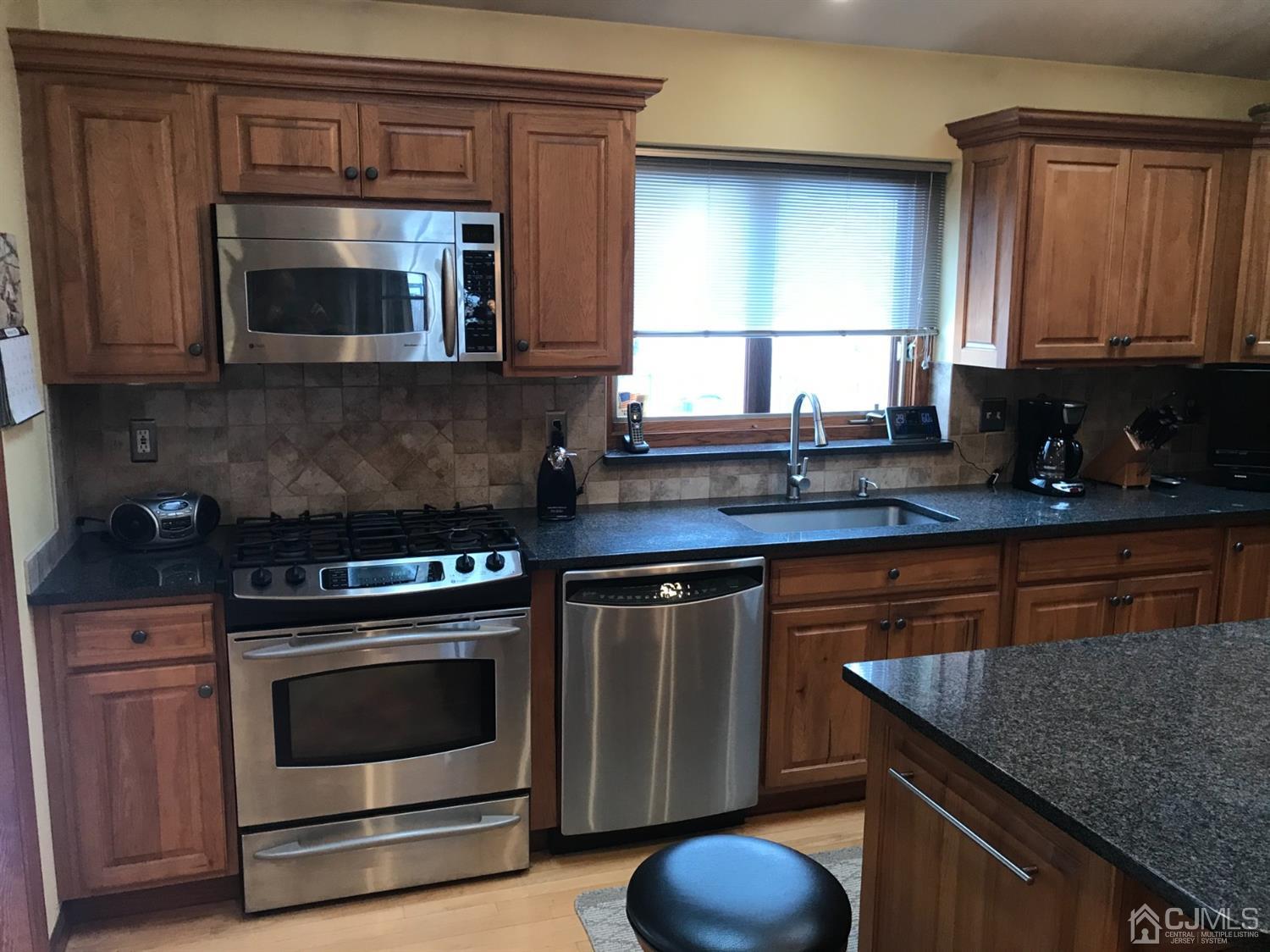 10 Wilcox Road New Brunswick, NJ 08901 - Photo 21 of 41 a kitchen with granite countertop a stove top oven microwave and cabinets