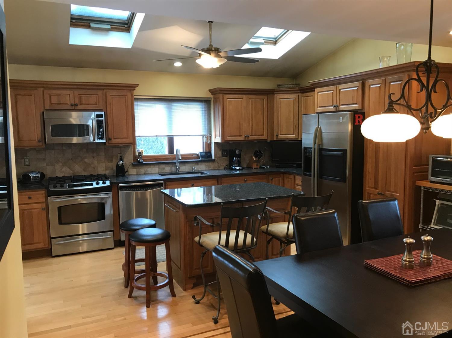 10 Wilcox Road New Brunswick, NJ 08901 - Photo 24 of 41 a kitchen with granite countertop a stove a sink a dining table and chairs with wooden floor