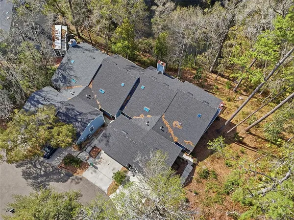 an aerial view of a house with a yard and trees all around