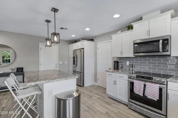 a kitchen with stainless steel appliances kitchen island granite countertop a sink a stove a refrigerator and cabinets