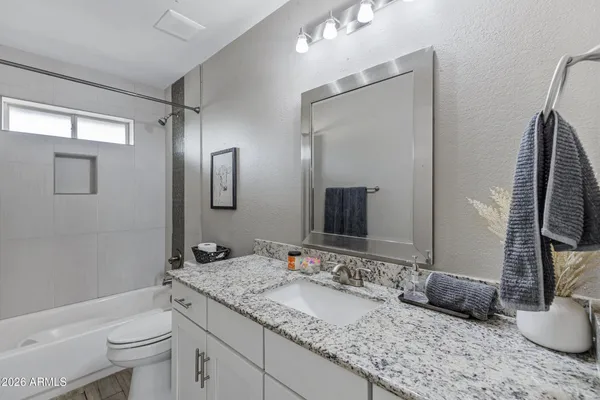 a bathroom with a granite countertop sink toilet and mirror