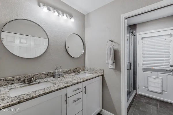 a bathroom with a granite countertop double vanity sink and a mirror