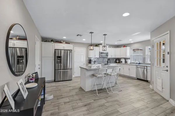 a kitchen with stainless steel appliances a dining table chairs a refrigerator and cabinets