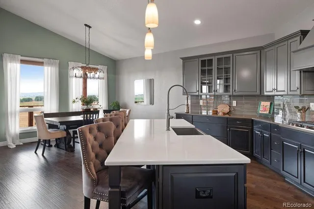 a large kitchen with a table chairs sink and wooden floor