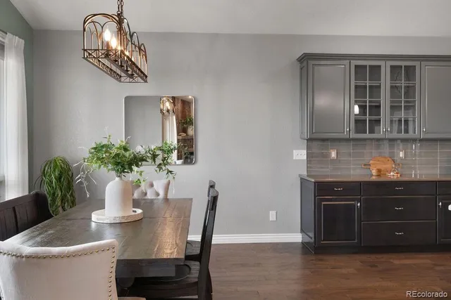 a dining room with wooden floor a chandelier a wooden table and chairs
