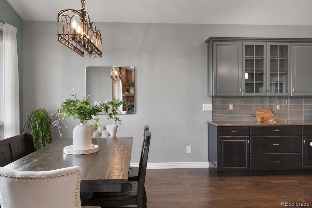 3050 Native Court Wellington, CO 80549 - Photo 16 of 50 a dining room with wooden floor a chandelier a wooden table and chairs