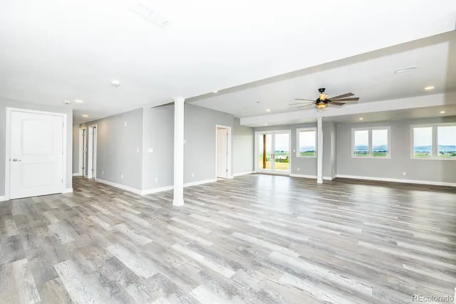 a view of an empty room with window and wooden floor