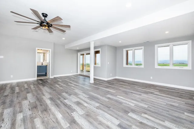 a view of an empty room with window and wooden floor
