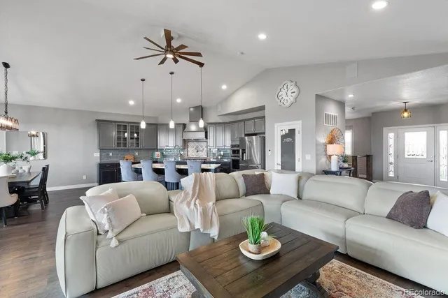 a living room with furniture kitchen view and a chandelier