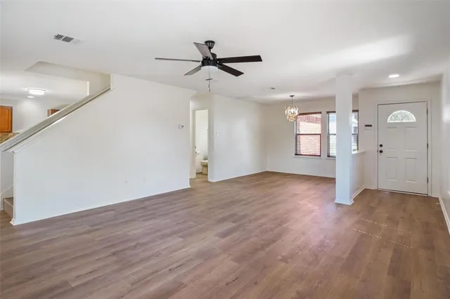a view of empty room with wooden floor and ceiling fan