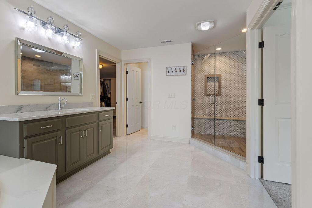 2570 Jewett Road Powell, OH 43065 - Photo 53 of 104 • Porcelain tile flooring • Ivory painted walls • Garden tub with cultured marble surround • Linen cabinet • His & hers vanity with single bowl, granite sinktops • (2) 4 bulb wall lights • Shower stall with glass doors & ceramic tile surround