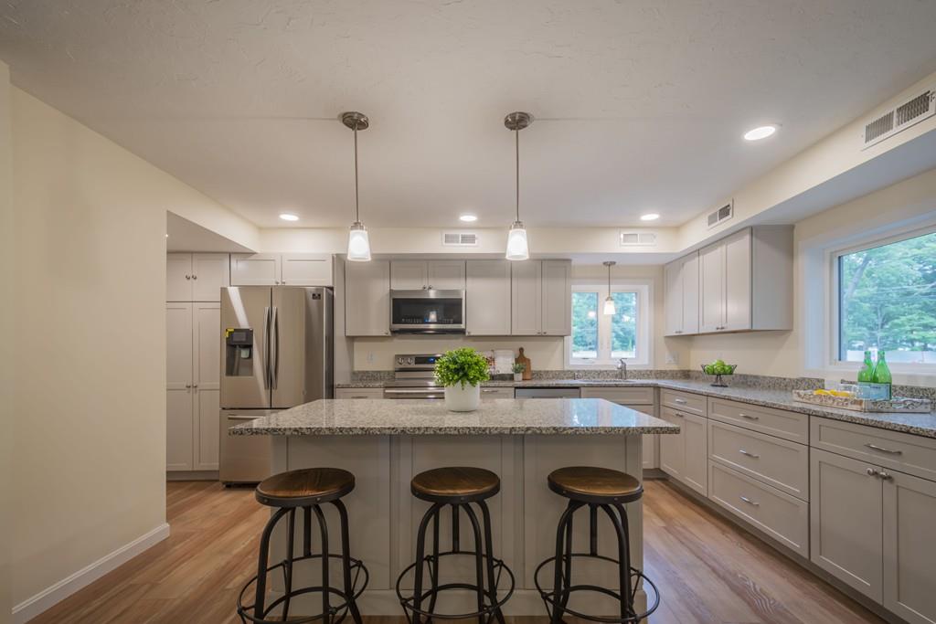 1 Kingman Road Acton, MA 01720 - Photo 14 of 42 a kitchen with stainless steel appliances kitchen island granite countertop a sink a stove a dining table and chairs with wooden floor