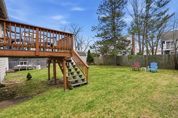 a view of a house with a small yard and a wooden deck