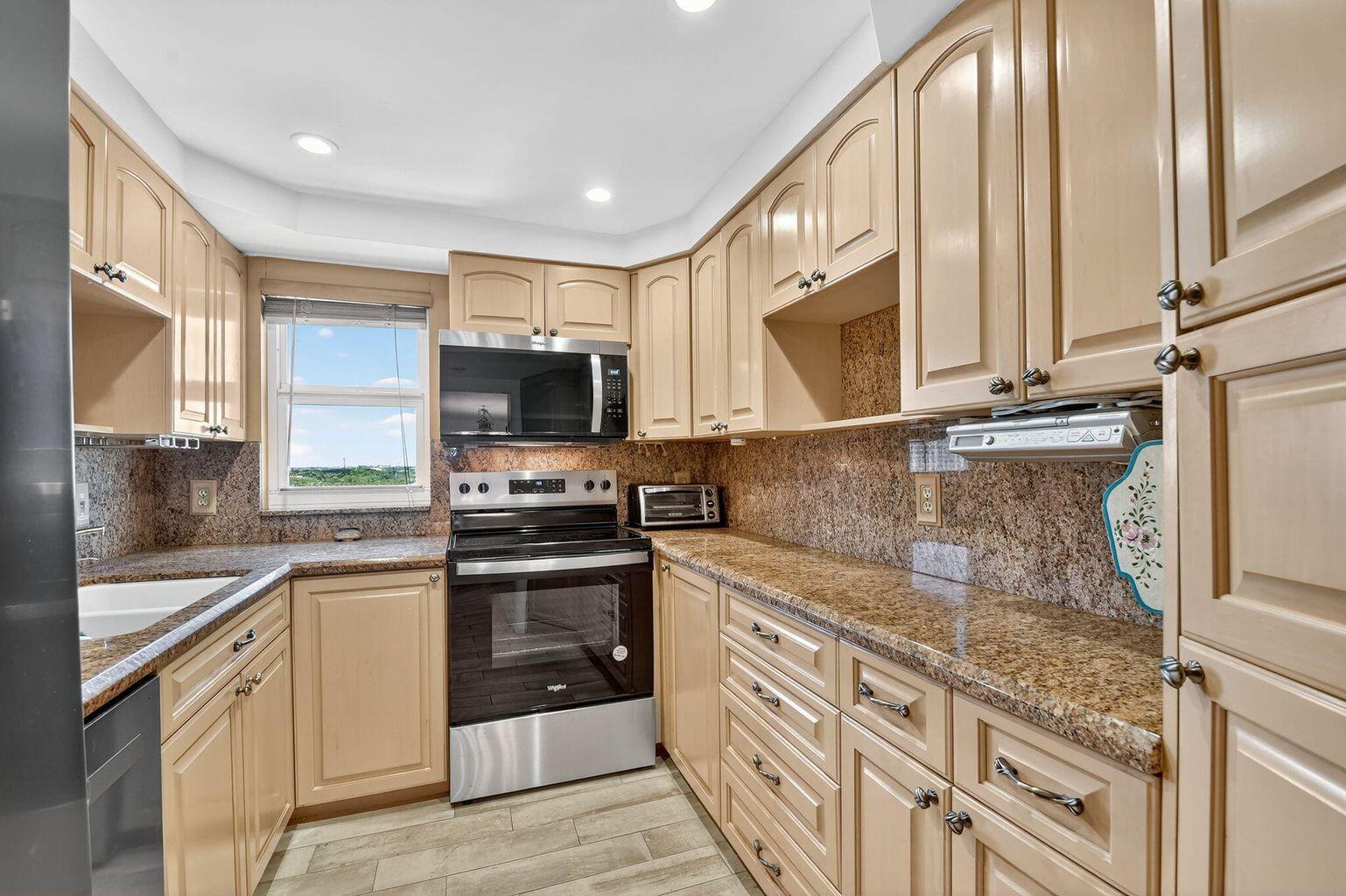 4511 South Ocean Boulevard, Unit 701 Highland Beach, FL 33487 - Photo 3 of 16 a kitchen with stainless steel appliances granite countertop a stove microwave and sink