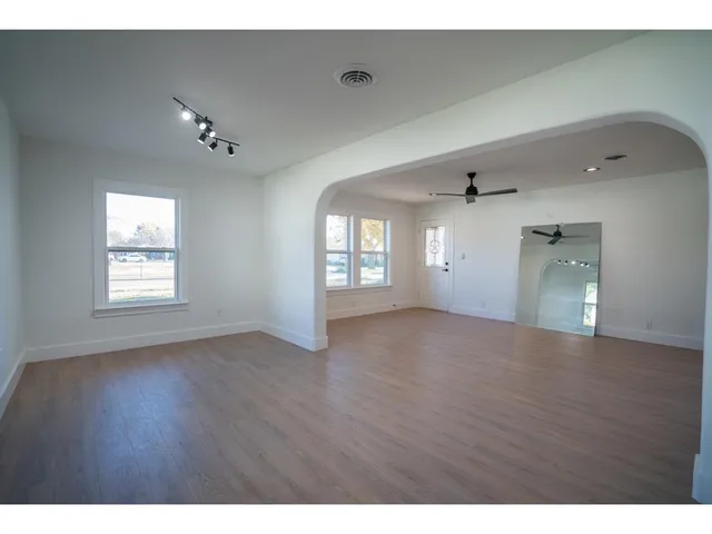 a view of an empty room with window and wooden floor