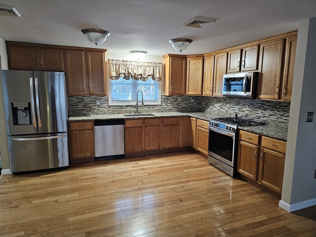 223 Charge Pond Road Wareham, MA 02571 - Photo 3 of 10 a kitchen with stainless steel appliances granite countertop wooden cabinets a refrigerator a stove a sink and dishwasher with wooden floor
