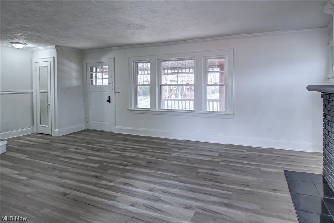 4764 Rockwood Road Cleveland, OH 44125 - Photo 8 of 35 Unfurnished living room with a healthy amount of sunlight, dark wood-type flooring, a textured ceiling, and crown molding