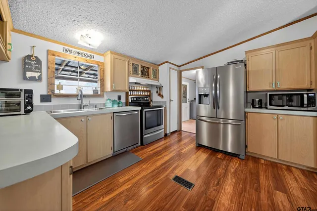 a kitchen with stainless steel appliances granite countertop a stove top oven a sink dishwasher and cabinets with wooden floor