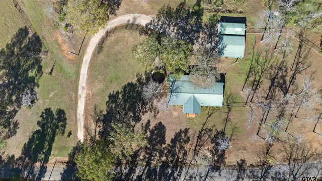 an aerial view of residential house with outdoor space and trees all around