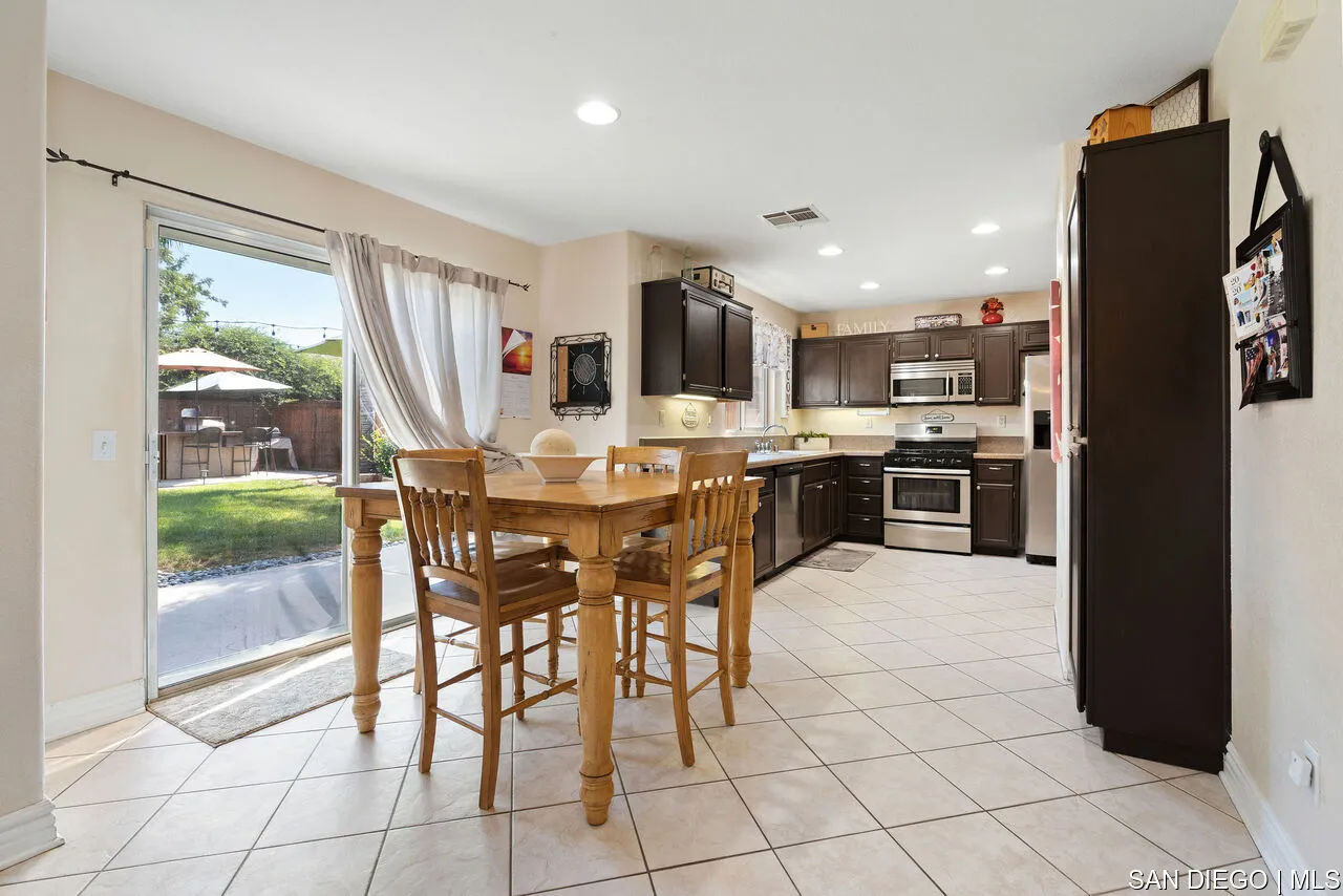 27201 Wildsmith Road Menifee, CA 92584 - Photo 8 of 24 a dining hall with stainless steel appliances a stove a refrigerator a kitchen island a stove top oven a sink with a dining table and chairs