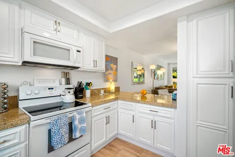 a kitchen with white cabinets and refrigerator