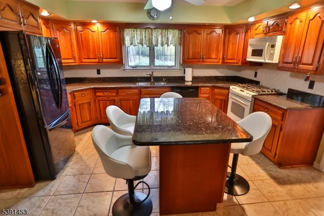 a kitchen with stainless steel appliances granite countertop a sink a table and chairs