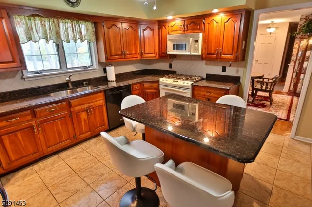 a kitchen with stainless steel appliances granite countertop a sink a counter space and a large window