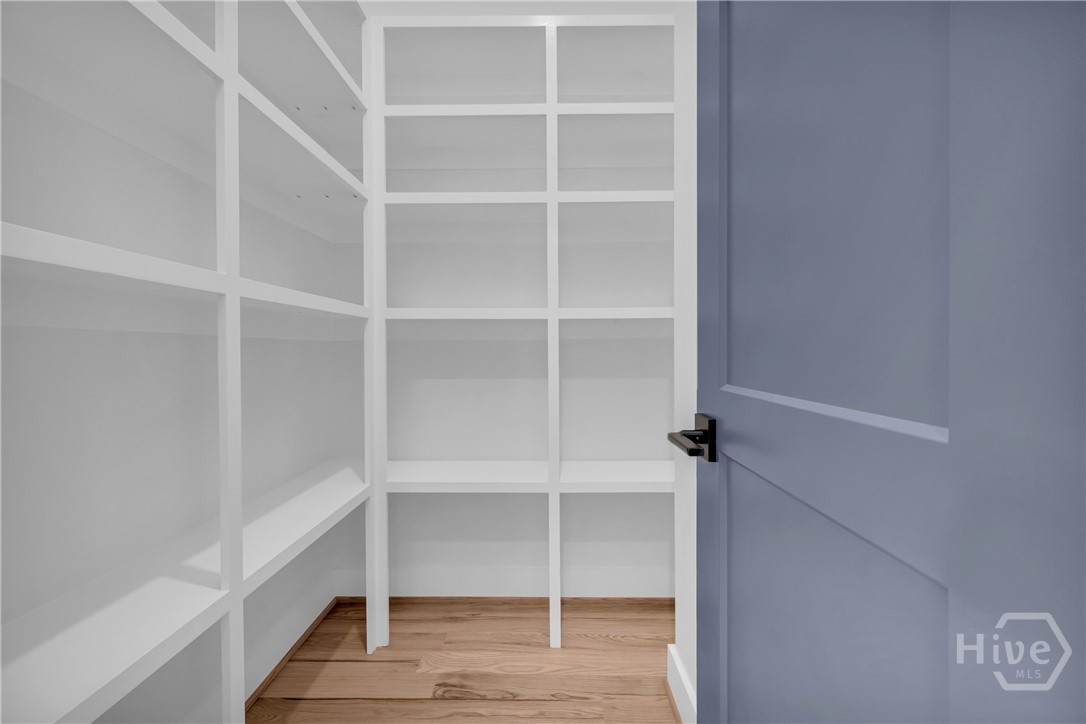 2476 St Martin Way Monroe, GA 30656 - Photo 15 of 75 Custom built-in shelving with white finishes, wood-finish flooring, and a contemporary panel door with matte black hardware