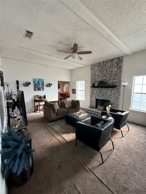 509 Bethlehem Street Terrell, TX 75160 - Photo 10 of 13 Carpeted living room with a stone fireplace, a textured ceiling, and ceiling fan