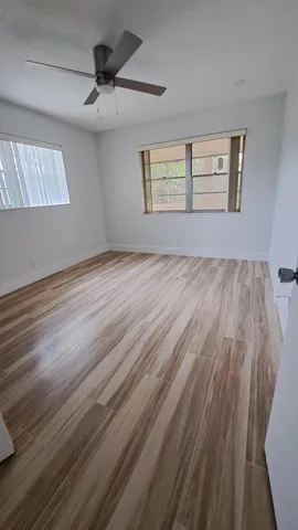 a view of an empty room with a window and wooden floor