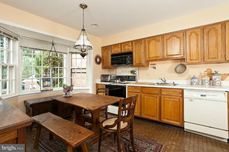 6617 Weymouth Road Baltimore, MD 21212 - Photo 4 of 30 a kitchen with stainless steel appliances granite countertop a stove top oven a sink a dining table and chairs with wooden floor