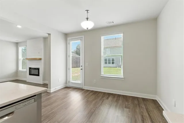 an empty room with wooden floor fireplace and windows