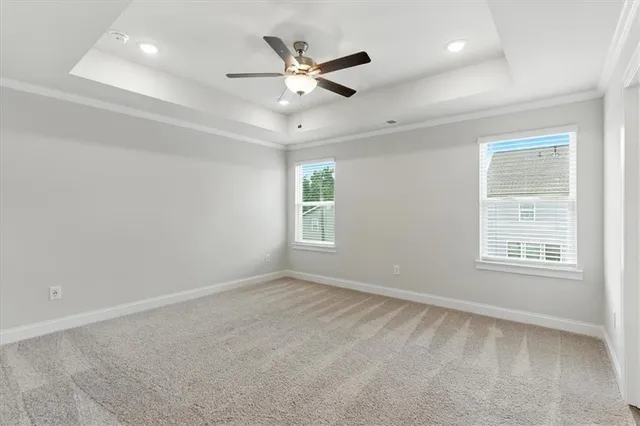 an empty room with ceiling fan and windows