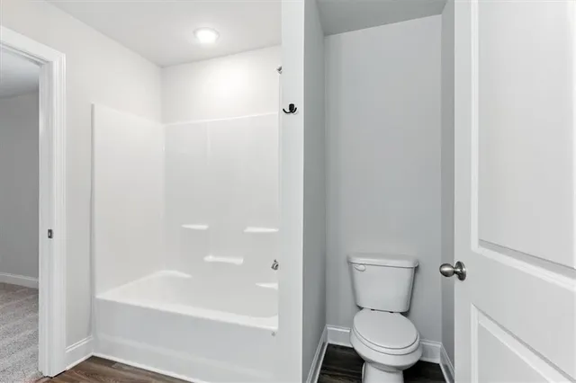 a white toilet sitting next to a bath tub