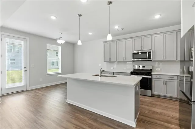 a kitchen with stainless steel appliances granite countertop a sink a stove a microwave a center island and cabinets