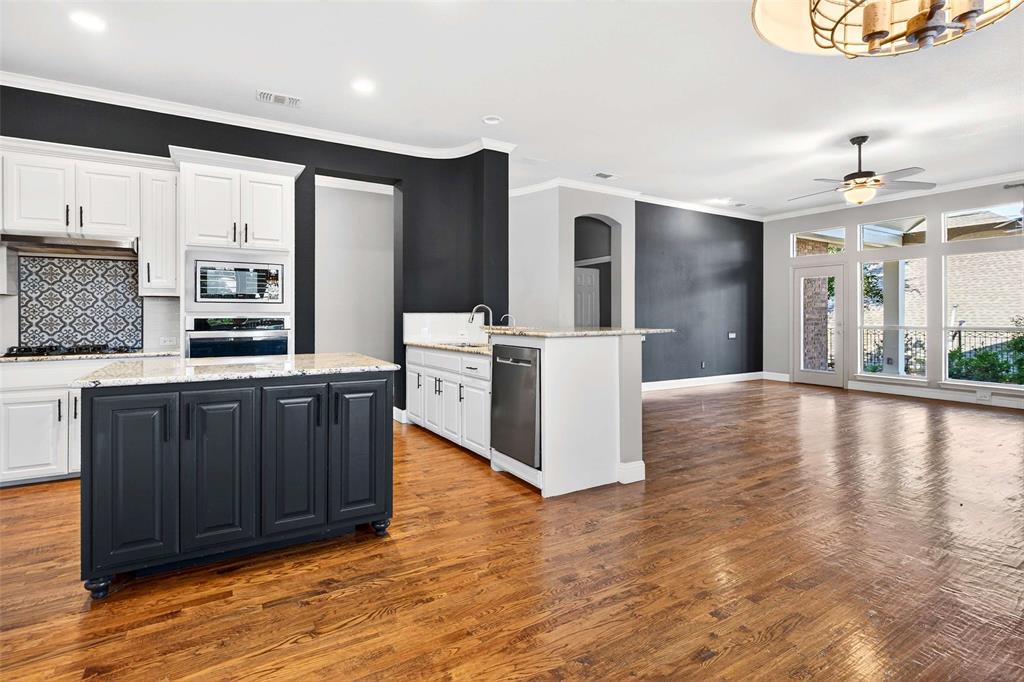 704 Scenic Ranch Circle Fairview, TX 75069 - Photo 11 of 40 a kitchen with stainless steel appliances granite countertop a stove top oven a sink dishwasher and a refrigerator with wooden floor