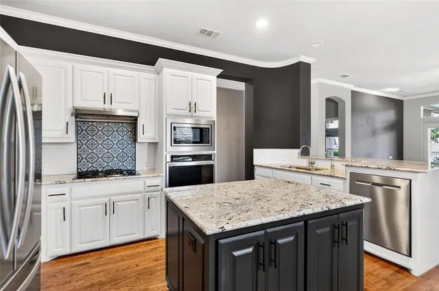 a kitchen with granite countertop a sink cabinets and stainless steel appliances