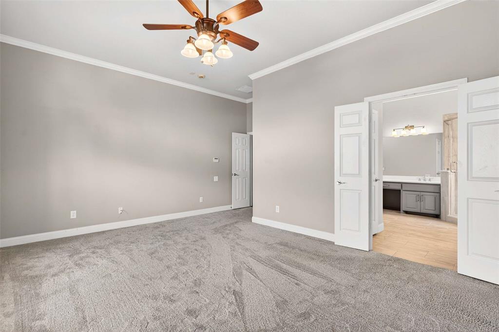 704 Scenic Ranch Circle Fairview, TX 75069 - Photo 20 of 40 an empty room with chandelier fan and kitchen view