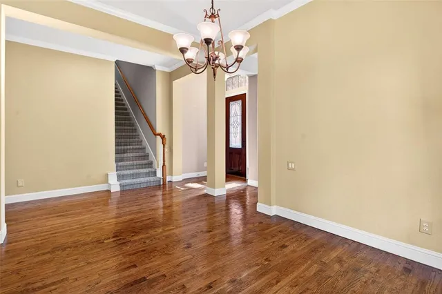 a view of an empty room with wooden floor and a chandelier