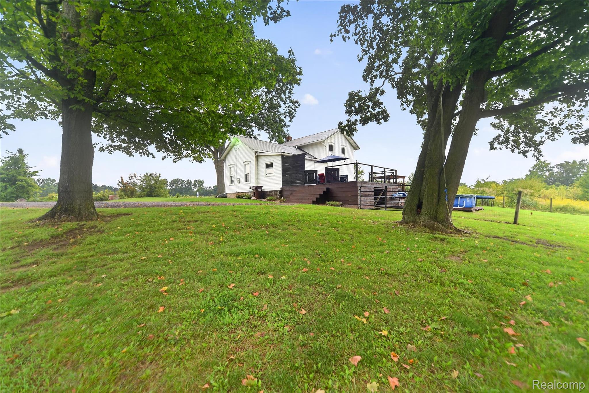9413 Rives Junction Road Rives Junction, MI 49277 - Photo 33 of 43 Expansive lawn with mature trees, a multi-level wood deck, white vinyl siding, and a partial black exterior