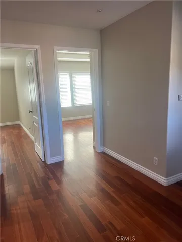 an empty room with wooden floor and mirror